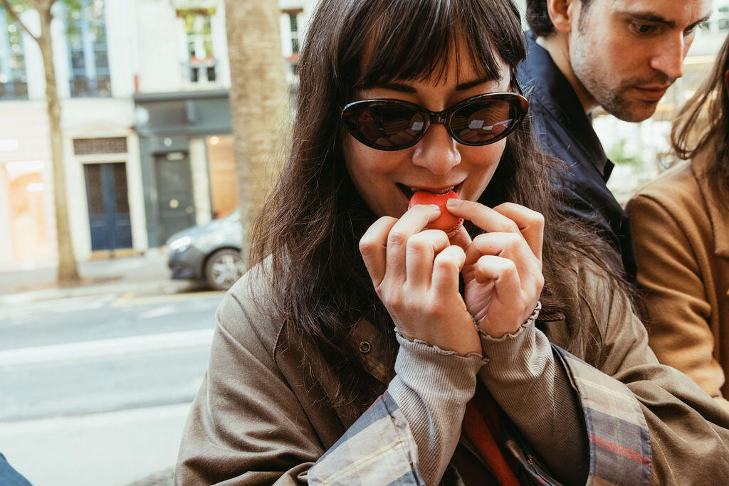 a guest on an Eating Europe Paris food tour biting into a French macaron and smiling